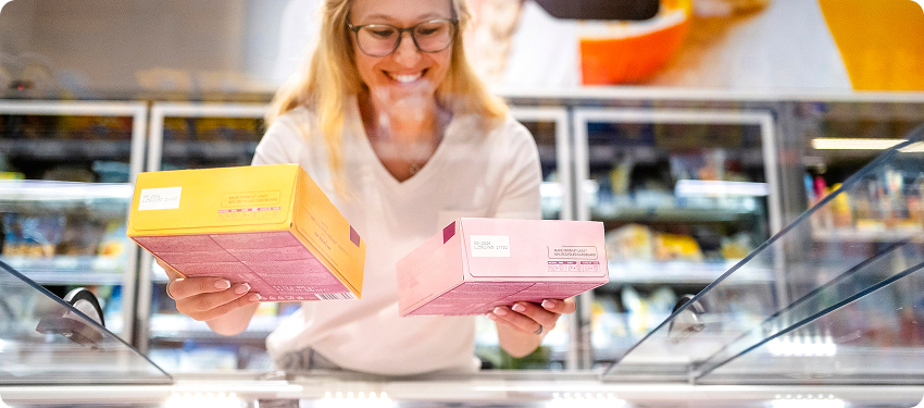 Shopper comparing product boxes in a grocery aisle