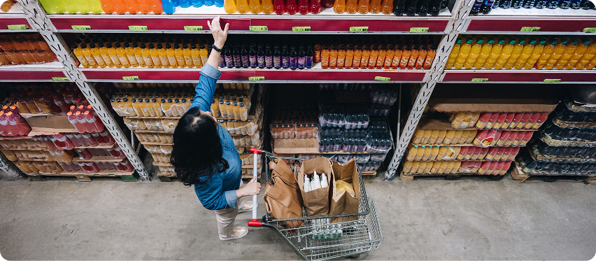 Shopper reaching for a beverage in a grocery aisle